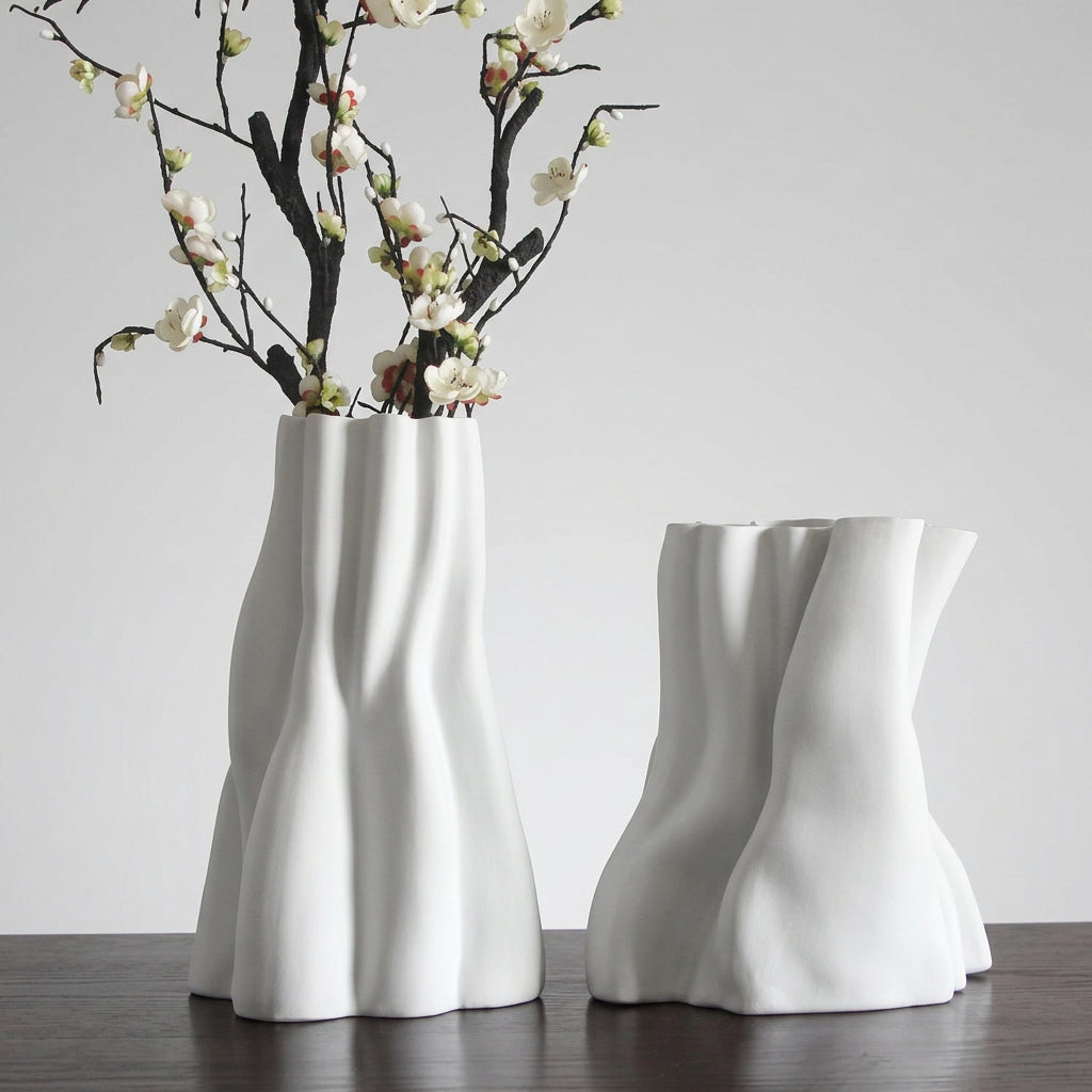 Set di vasi bianchi con forme scultoree ondulate e rami fioriti