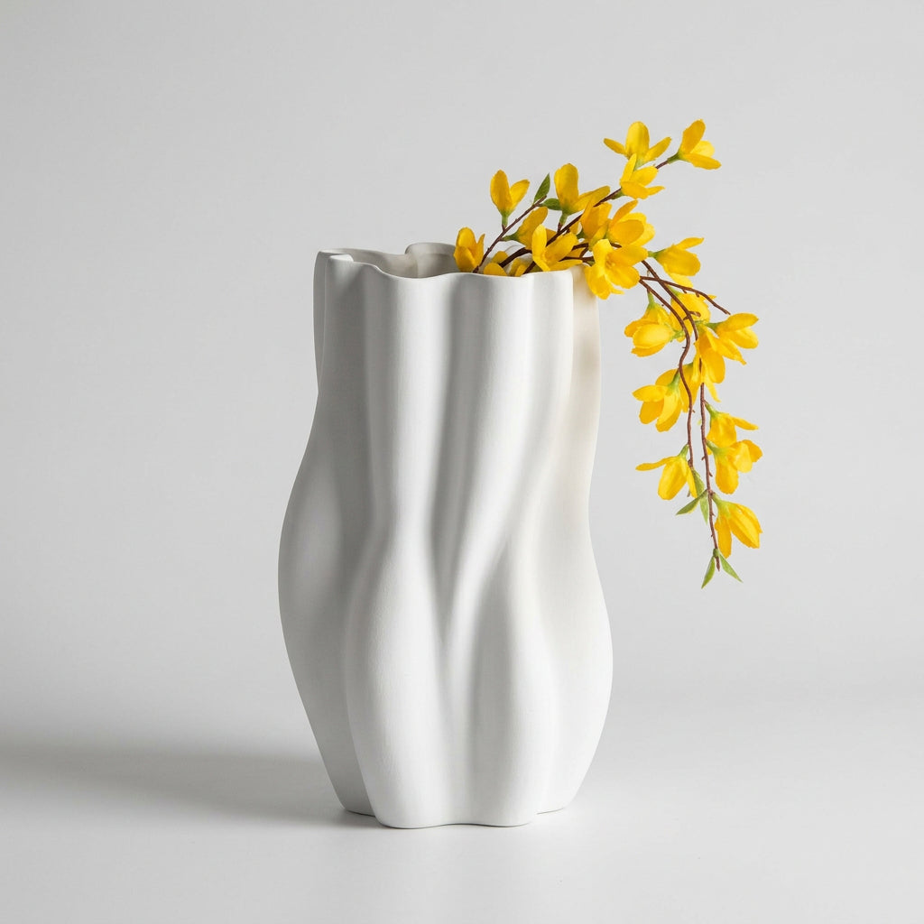 Vaso bianco scultoreo con superficie ondulata e ramo di fiori gialli