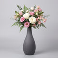 Vaso grigio con rigature verticali e composizione di rose rosa e bianche