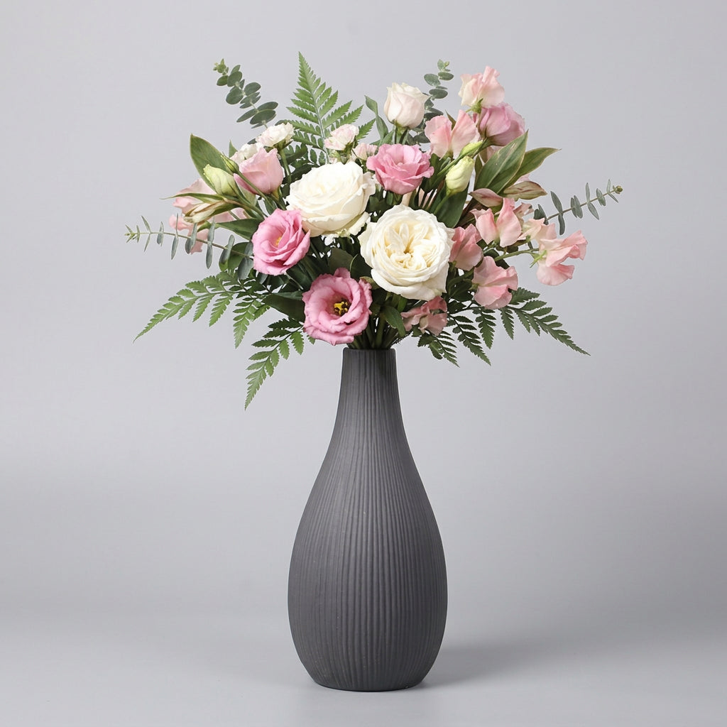 Vaso grigio con rigature verticali e composizione di rose rosa e bianche
