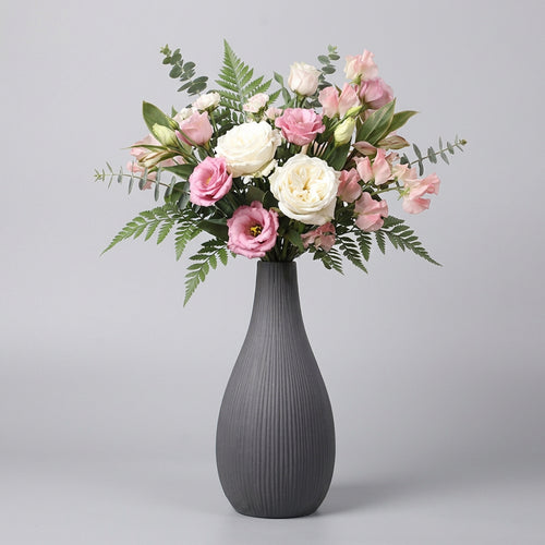 Vaso grigio con rigature verticali e composizione di rose rosa e bianche